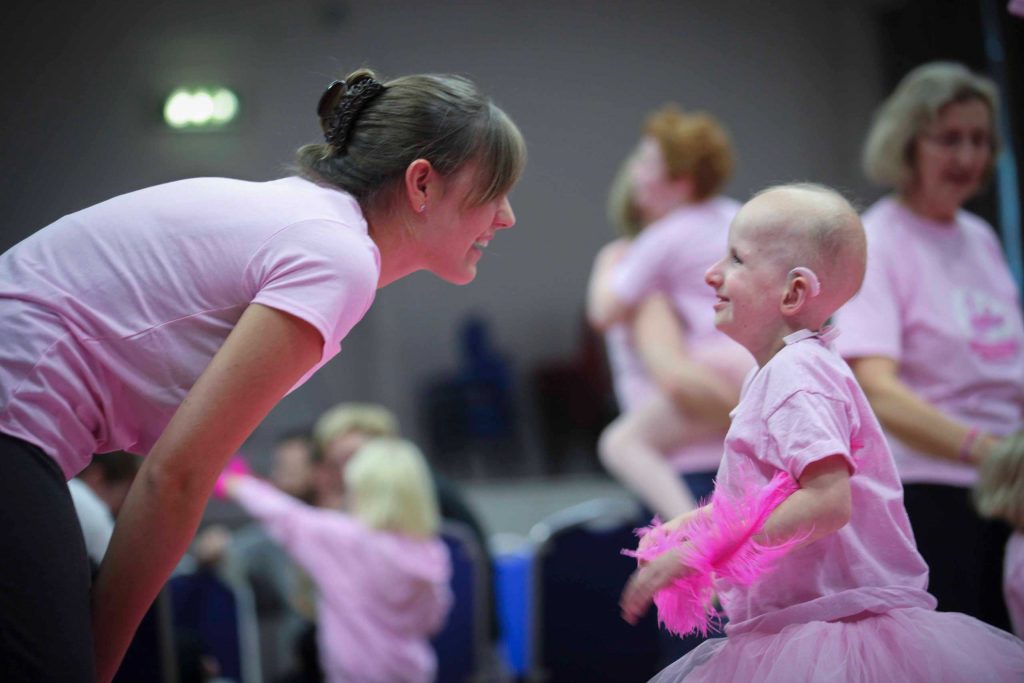 A dance teacher shares a smile with one of our Flamingo Chicks children