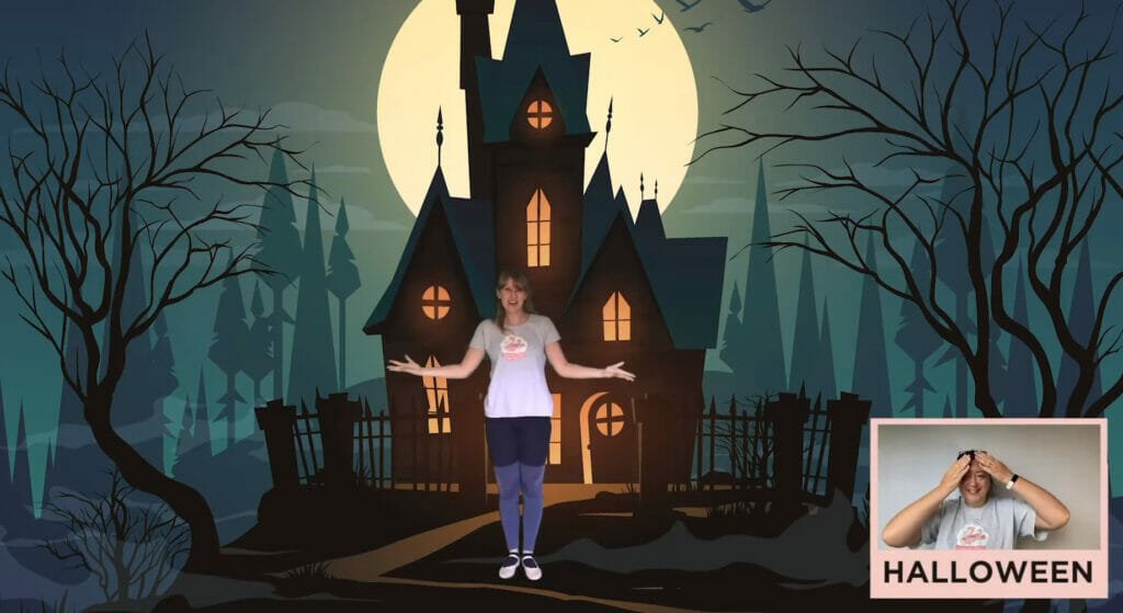 Halloween Spooktacular virtual class: Rhiannon stands in front of a haunted house at night with a full moon behind