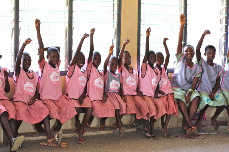 A group of pupils in Ghana raise their arms to create a Flamingo neck