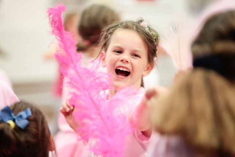 A girl plays with a huge pink feather in a Flamingo Chicks class